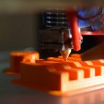 3D Printing - a close up of an orange object with a pencil