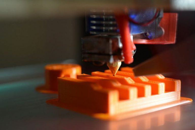 3D Printing - a close up of an orange object with a pencil