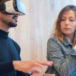 VR Meeting - A Woman Sitting Besides a Man Wearing VR Goggles