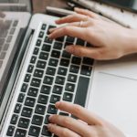 5G Remote Work - From above of unrecognizable woman sitting at table and typing on keyboard of computer during remote work in modern workspace