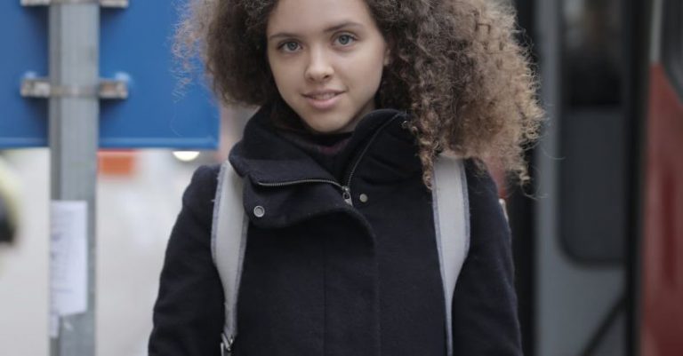 Smart Bus Stop - Serious young lady with book standing on bus stop on street