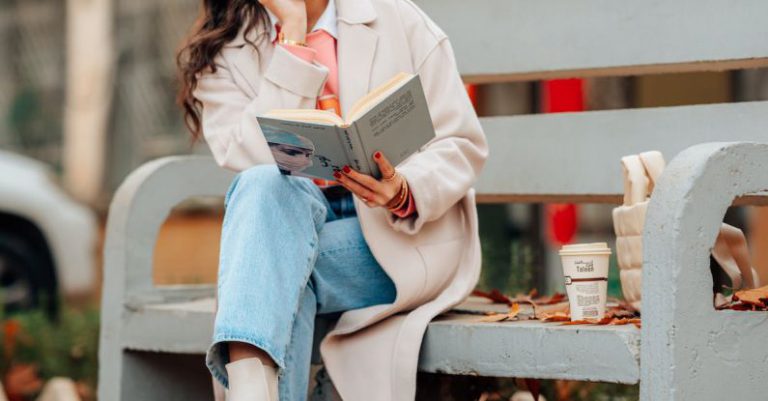 Urban Park - Young Woman Sitting on a Bench with a Book and Coffee