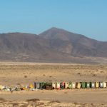 Recycling Bins - Row of Recycling Bins and a Pile of Garbage by the Road in the Desert