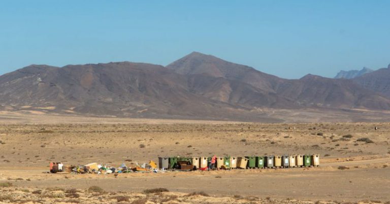 Recycling Bins - Row of Recycling Bins and a Pile of Garbage by the Road in the Desert