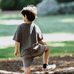 Exoplanet Discovery - Boy in White T-shirt and Blue Shorts Sitting on Rock Near Body of Water during