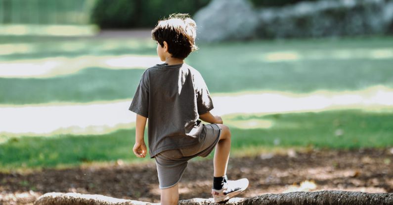 Exoplanet Discovery - Boy in White T-shirt and Blue Shorts Sitting on Rock Near Body of Water during