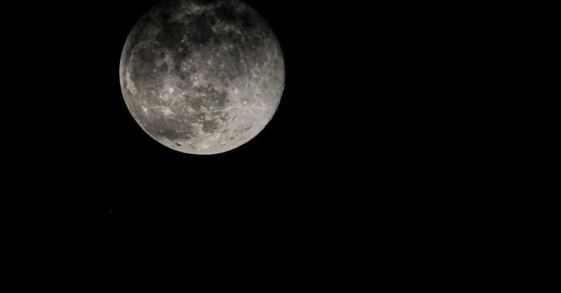 Satellite Orbit - Full moon shining on black background