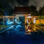 Smart House - reflection of blue light crossing above pool near house during nighttime