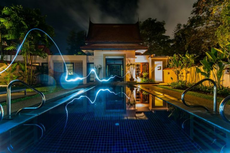 Smart House - reflection of blue light crossing above pool near house during nighttime