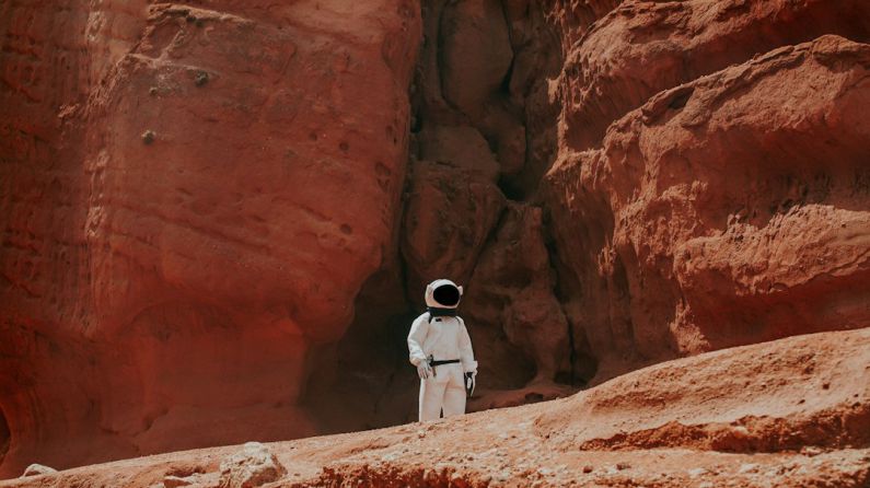 Mars Colonization - photography of astronaut standing beside rock formation during daytime