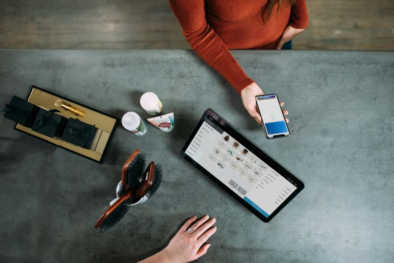 Square Payments - person holding smartphone beside tablet computer