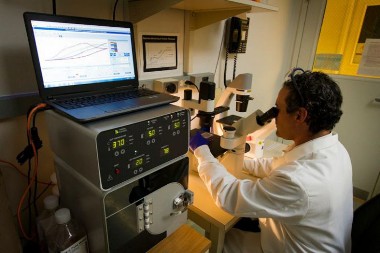 DNA Sequencing - man looking at microscope